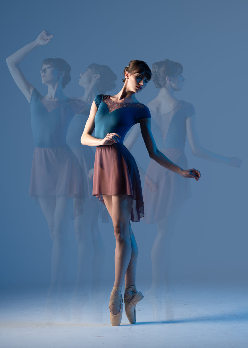 Ballet Rosa Createur Catalogue Women's Ninette Stretch Mesh Pull-On Skirt in Wild Rose Pink with dramatic high-low designs and stretch waistband, shown on a ballet dancer wearing the Sabine Leotard in contrasting Encre Bleu