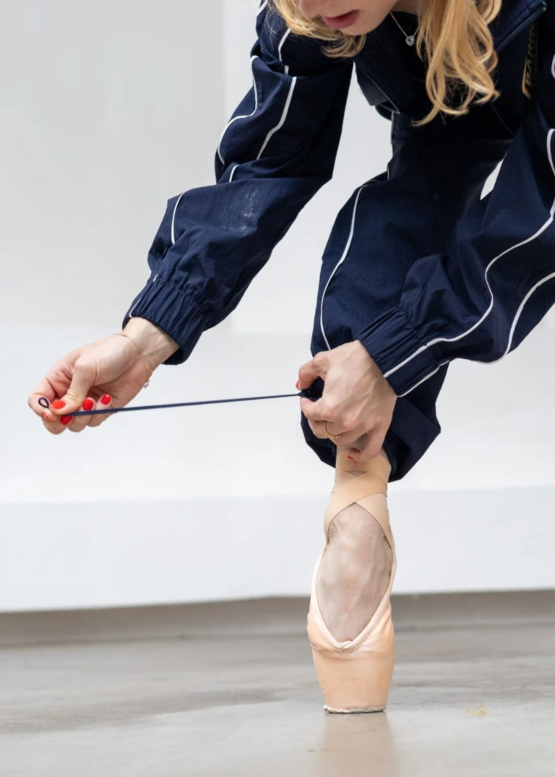 Barre Trash Tracksuit Pants in navy blue with elastic waistband, drawstring leg opening, and pinstripe details