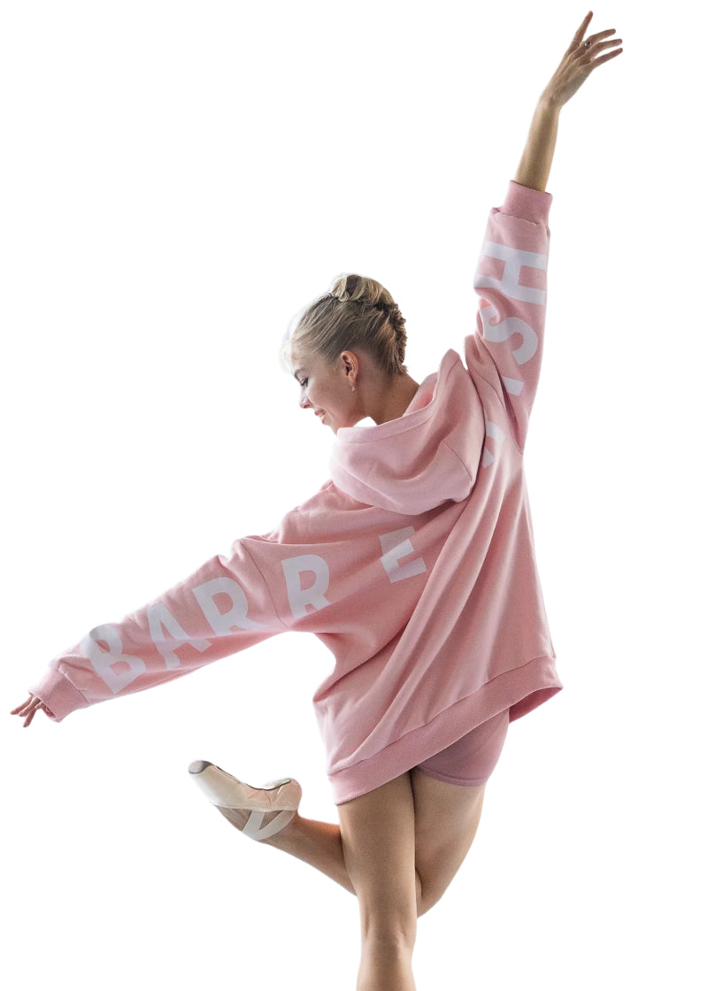 Barre Trash OH Oversized Hoodie in Ballerina Pink with white lettering, modeled by a ballet dancer