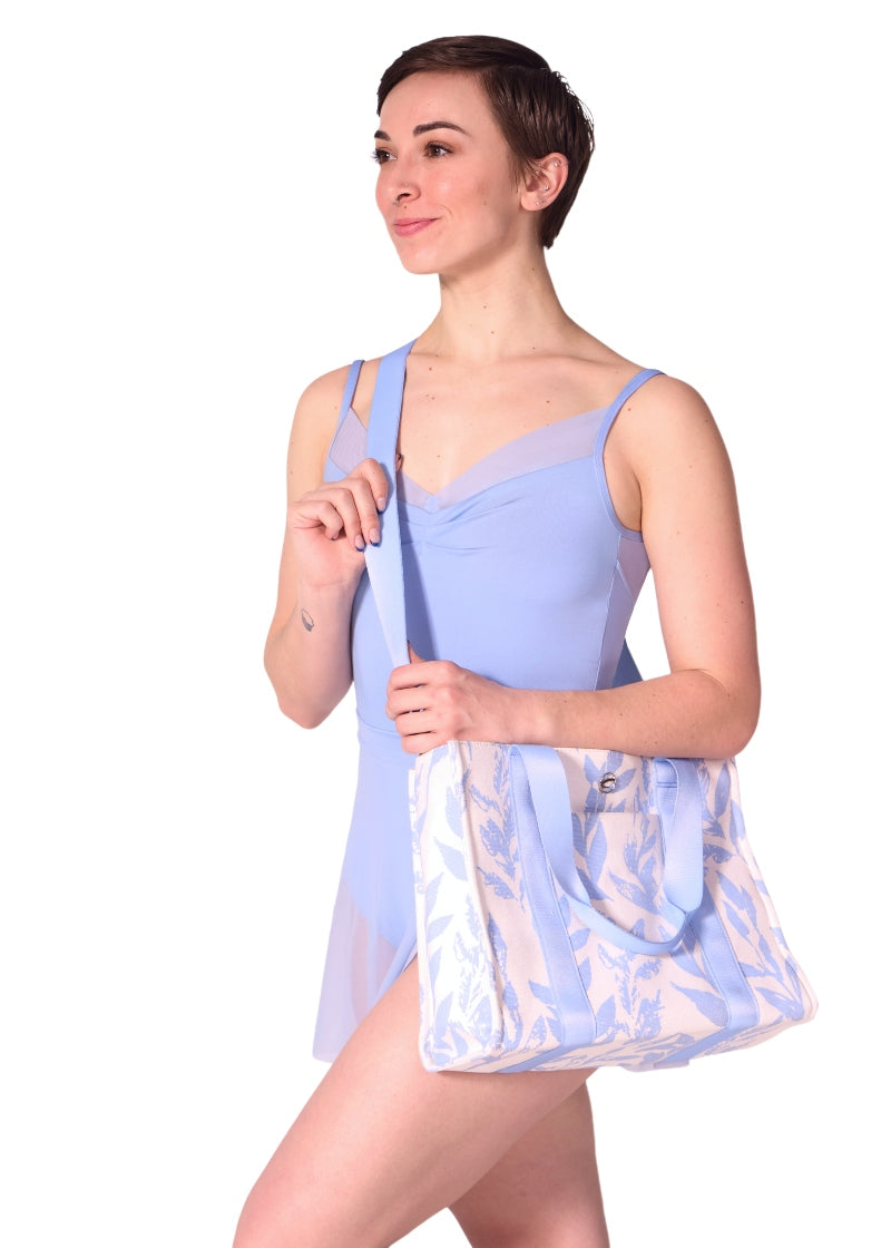 Capezio B316 Women's Soho Canvas Tote Bag in white and light blue floral Suble Leaf Horizon print made with 100% cotton twill and grosgrain handles and detachable adjustable shoulder strap shown on a ballet dancer