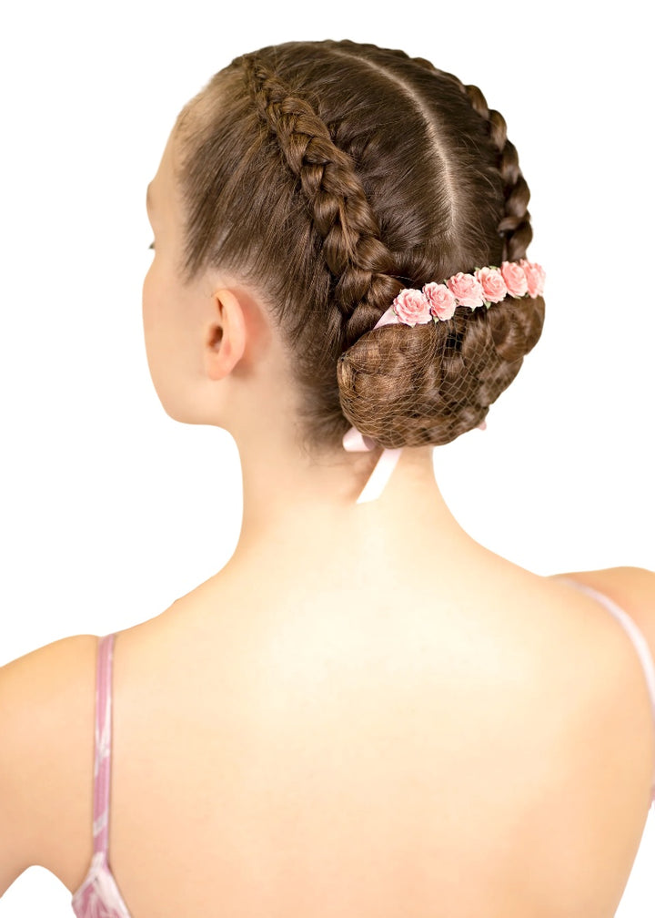 Light pink flowers and ribbon tied around a ballerina's bun.
