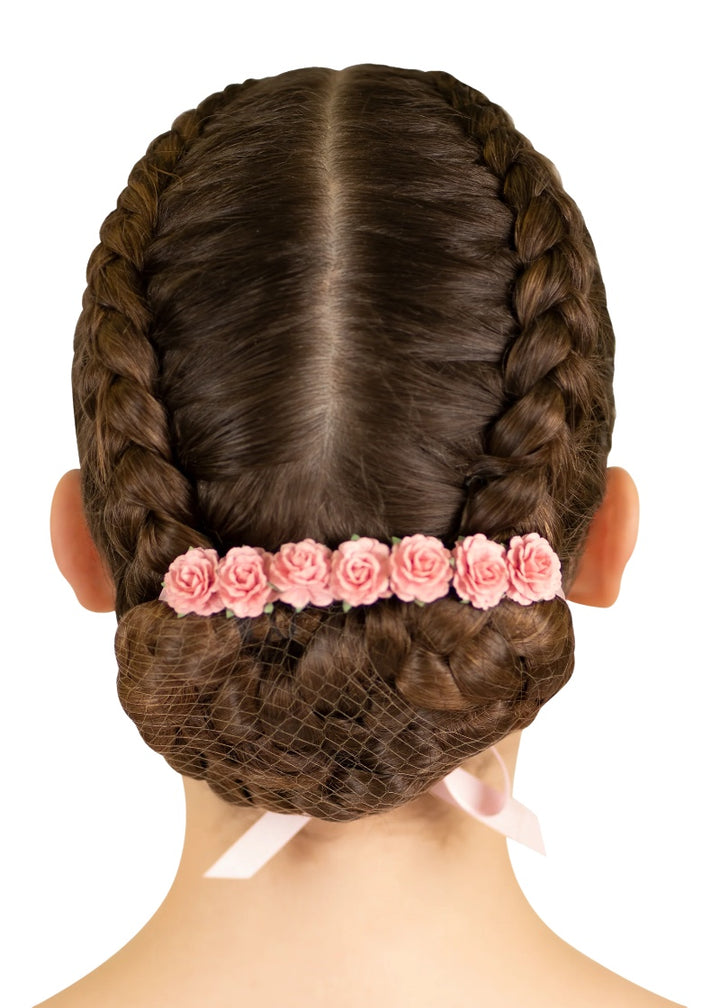 Light pink flowers and ribbon tied around a ballerina's bun.