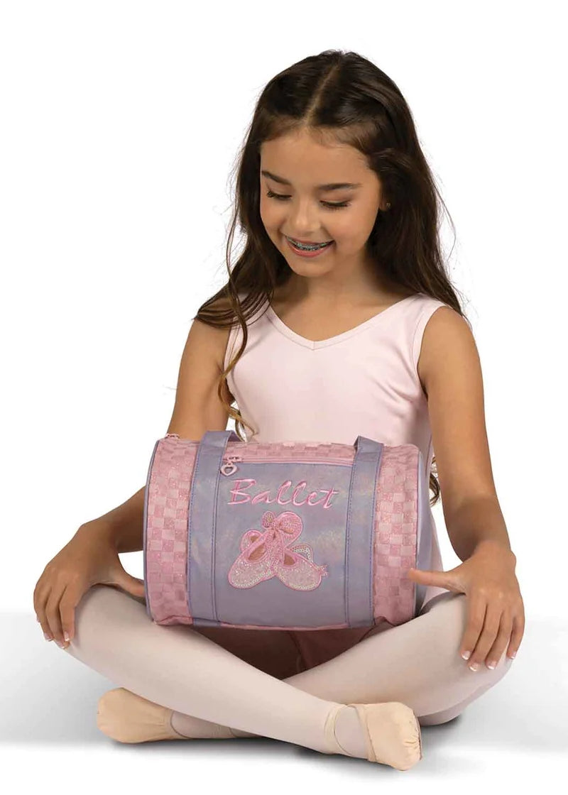 Dancer holding the Danznmotion small pink and purple ballet duffel with handle, exterior zip pocket, and embroidered ballet shoes