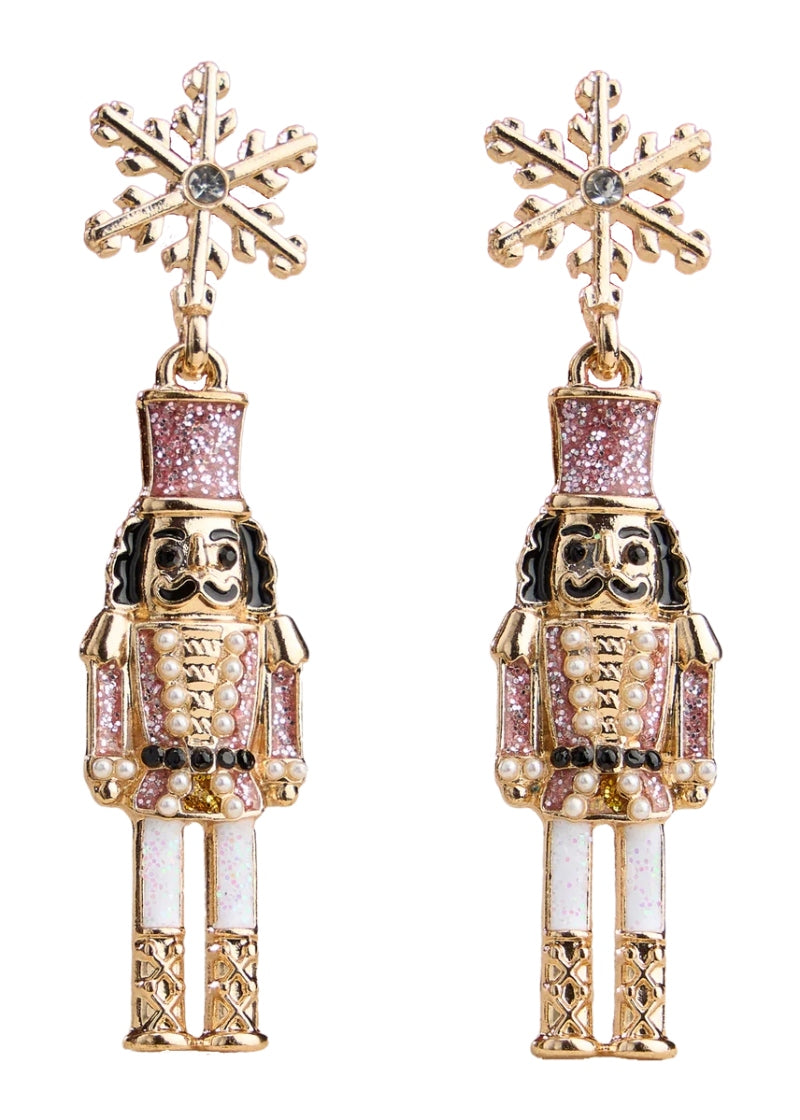 gold plated holiday nutcracker shaped earrings with pink and white enamel hanging from a snowflake-shaped post