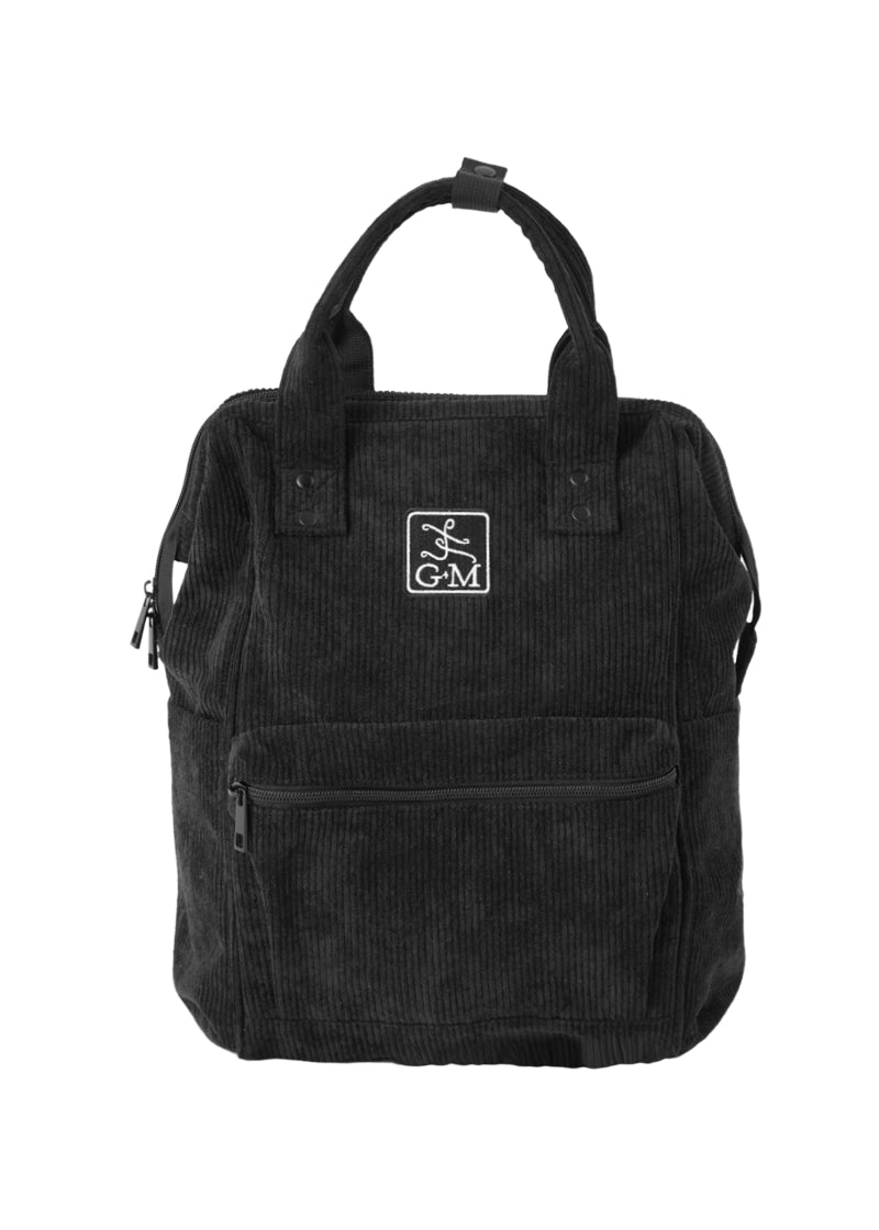 Gaynor Minden Studio backpack in black corduroy with white GM logo on the front, front zipper pocket, and zipper top closure.