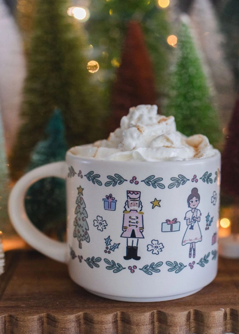 Ceramic mug with Nutcracker themed art holding a drink with whipped cream.