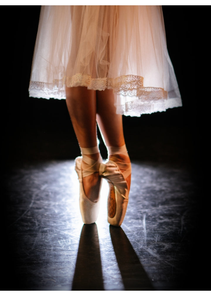 Dancer standing en pointe in sous-sus wearing Reveal Pointe Shoes and looking very chic in a vignette-style photo