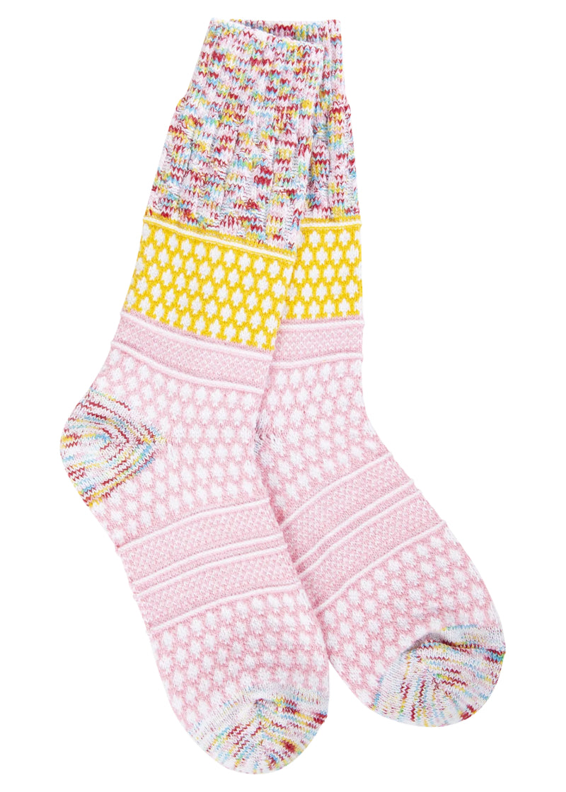 Knit crew socks with multicolored speckles on the toe, heel, and cuff, yellow and white diamond pattern on the ankle, and pink and white diamond pattern on the foot.